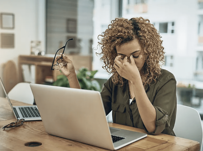stressed out person planning a conference pinching their nose behind an open laptop